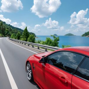 Red sports car driving fast along a scenic coastal road with tropical ocean view